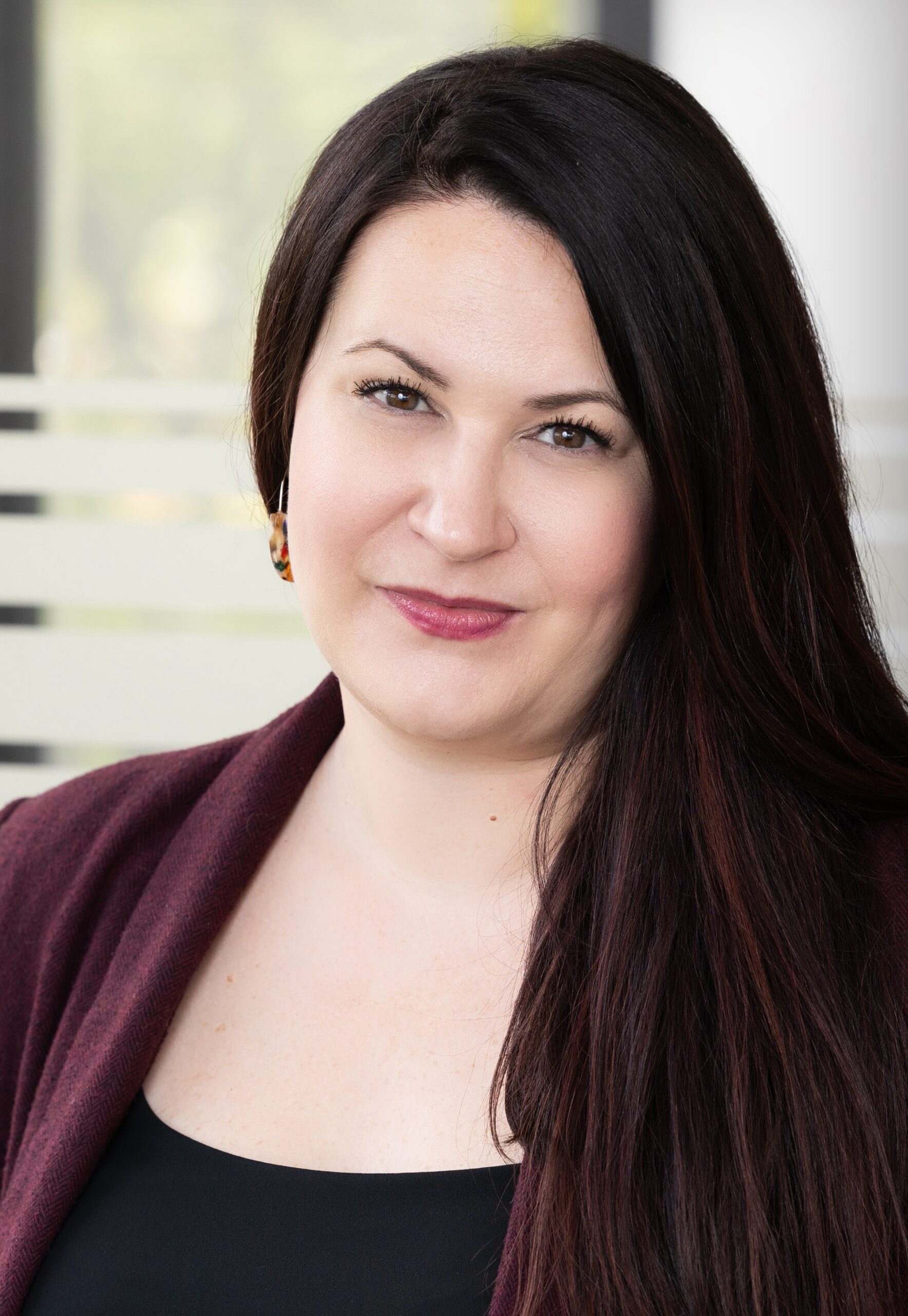 woman with dark hair wearing maroon jacket and black top