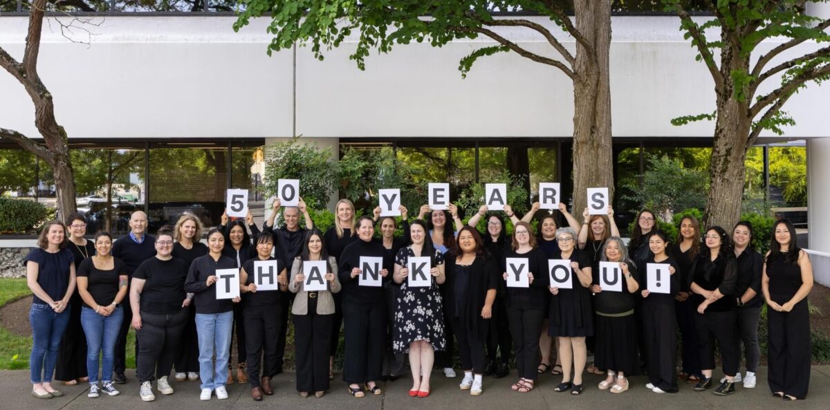 Group of KCSARC staff outdoors in front of office building holding individual letters that spell out the phrase "50 years thank you!"