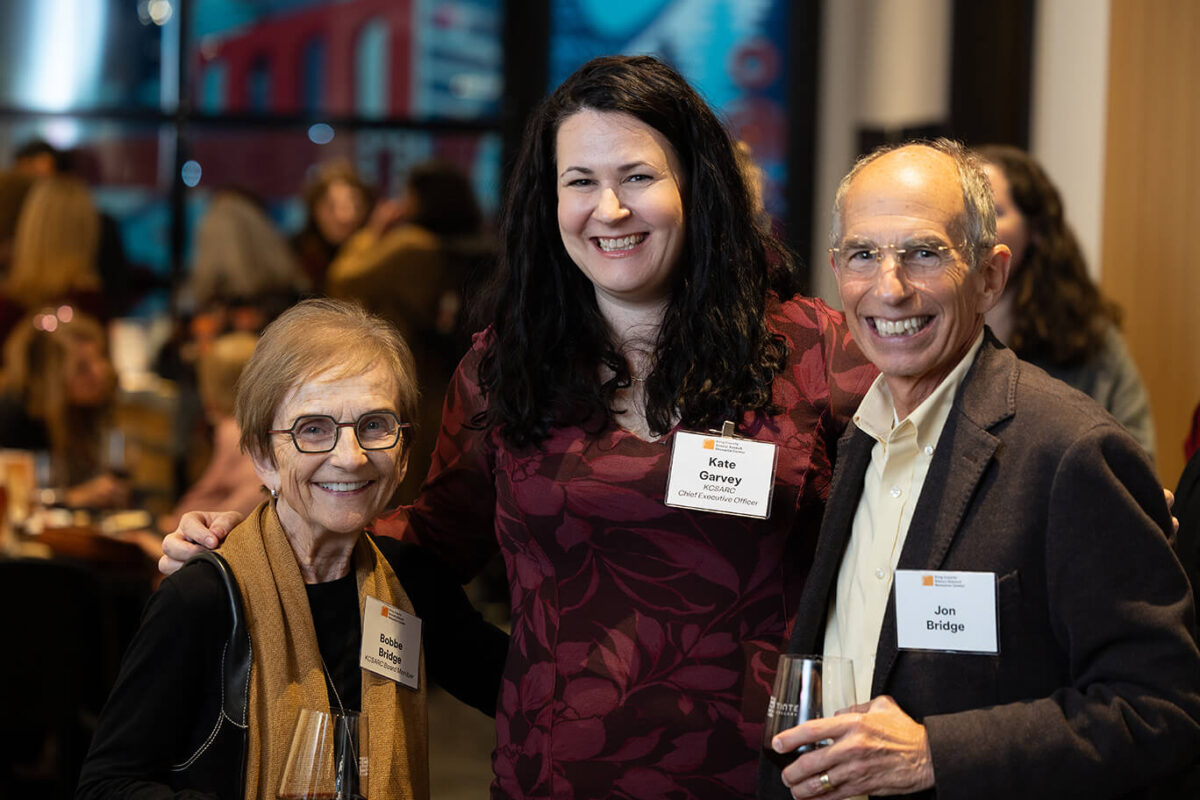 Three people pose and smile at a KCSARC fundraising event.