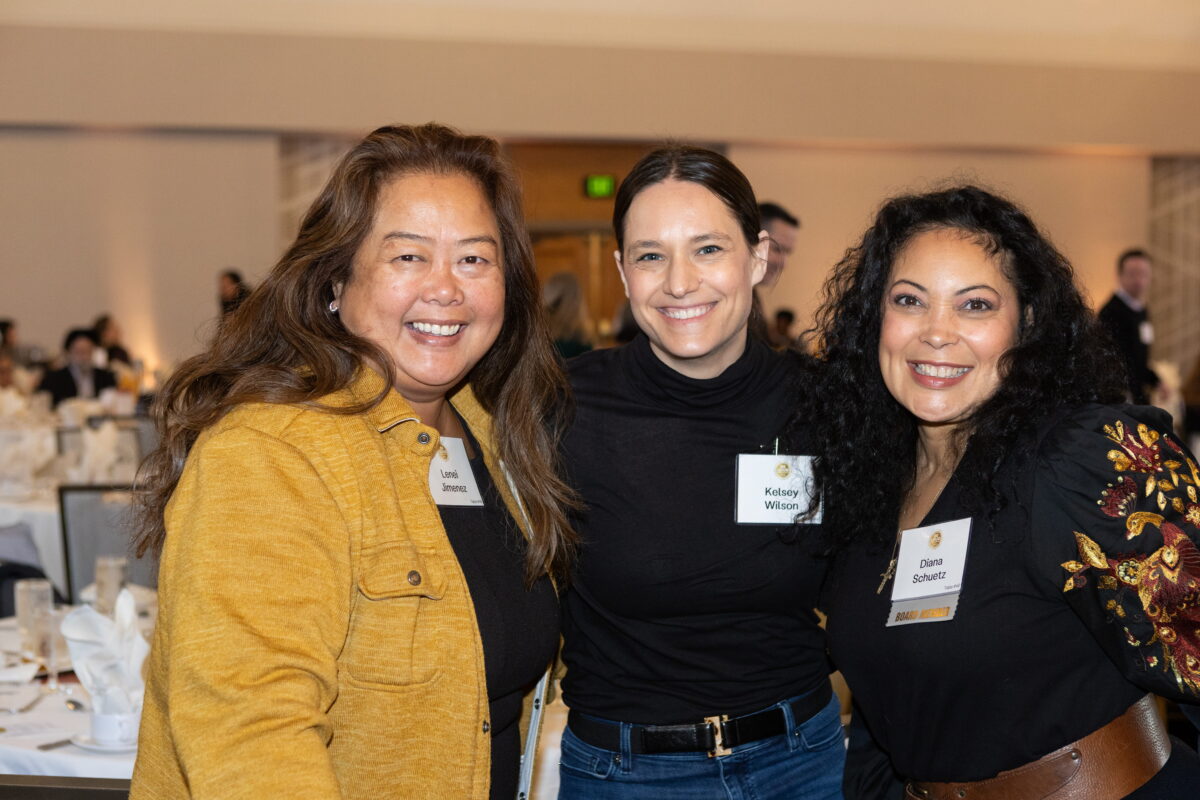 Three women smile and pose at KCSARC fundraising event.